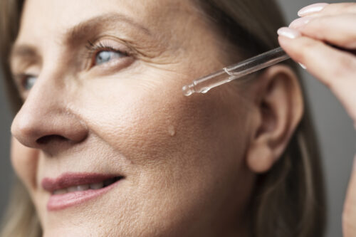 close-up-smiley-senior-woman-using-serum